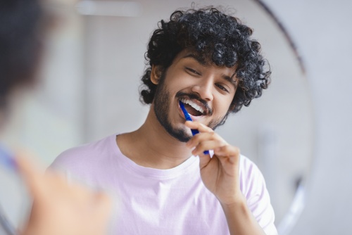 Man,Brushes,His,Teeth,In,Front,Of,A,Mirror