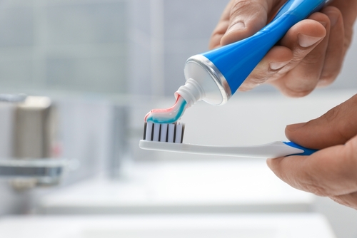 Man,Applying,Toothpaste,On,Brush,In,Bathroom